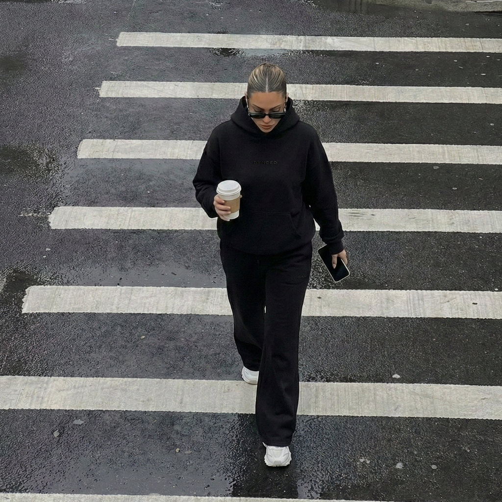 Person walking on a zebra crossing holding a coffee cup.