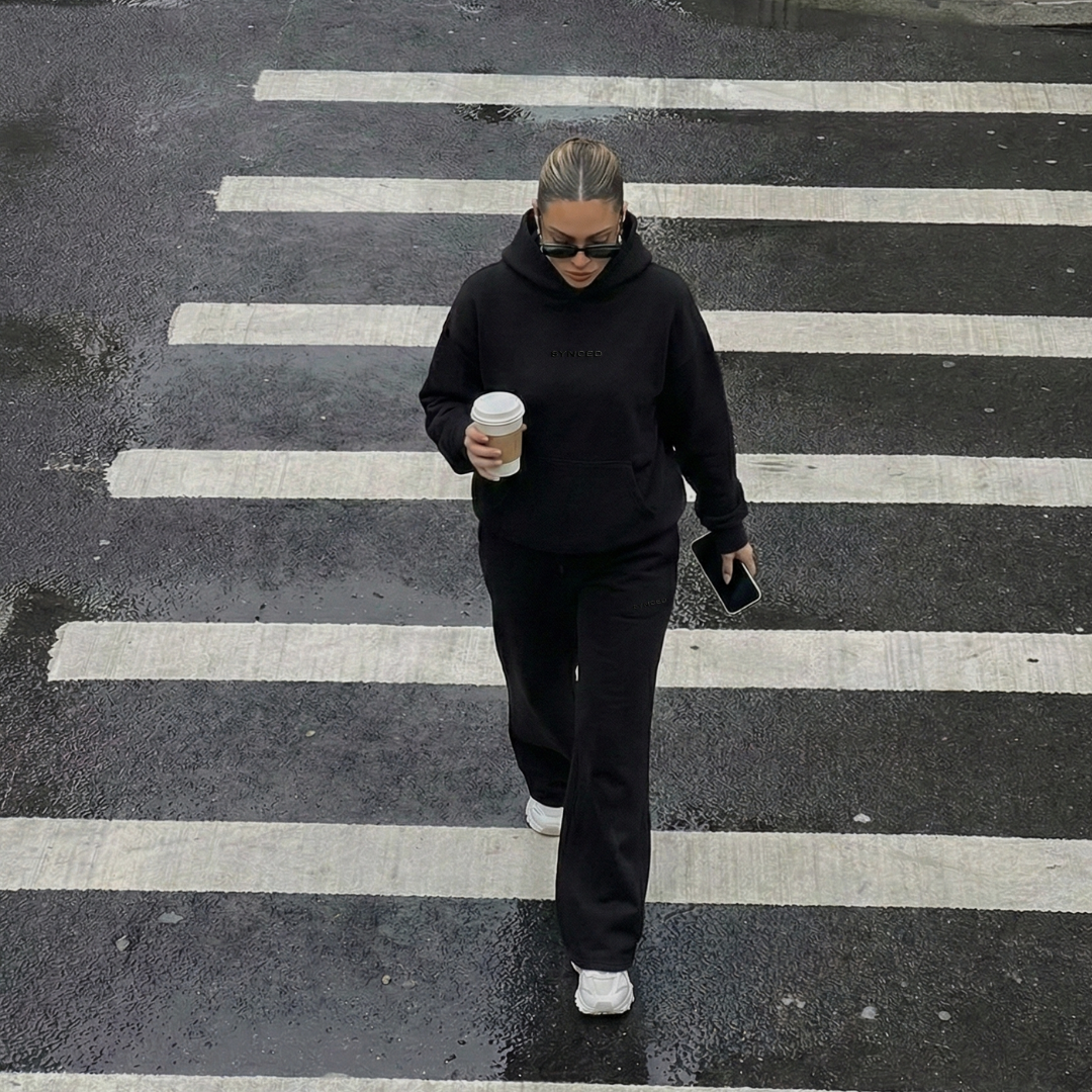 Person walking on a zebra crossing holding a coffee cup.