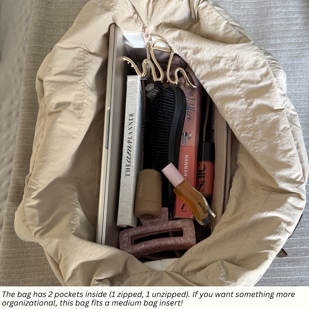 Beige bag with personal items including a hairbrush and hair clips on a textured surface.