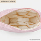 A light pink zippered pouch shown open to display its padded beige interior, with text labels reading 'PADDED BEIGE INTERIOR' and '2 side slip pockets inside' on a clean white background.